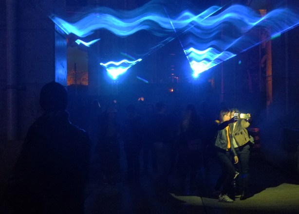 selfies in front of blue lights under the Gardiner at the Bentway, in front of Fort York, a light show called Waterlicht by Dutch artist Daan Roosegaarde
