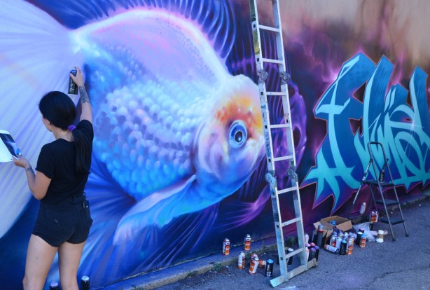 spray painting a mural of a fish swimming in the water 