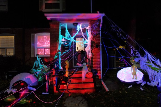 front porch and front yard of a house decorated with halloween, web, spiders, aliens, red lights, blue lights, 