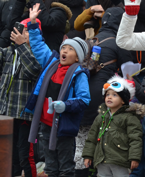 two young boys on the sidewalk enthusiastic cheering for the parade
