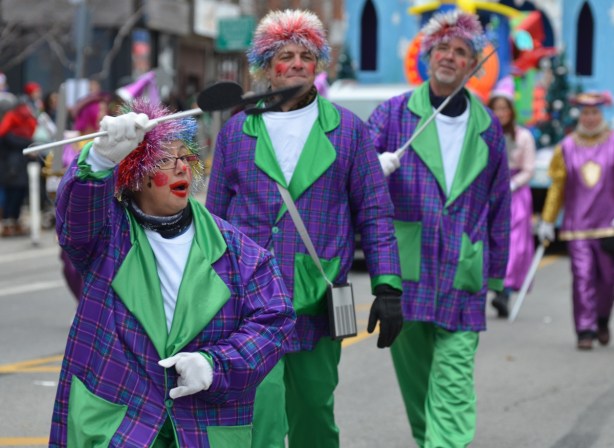 clowns in purple and green outfits and many colours in their wigs, walking in Santa Claus parade 