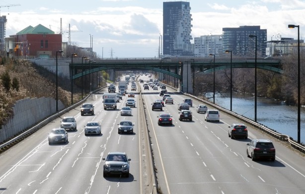looking south from a bridge over the Don Valley Parkway road, with cars driving north and south, looking towards bridge at Dundas Street, Don River to the right, 