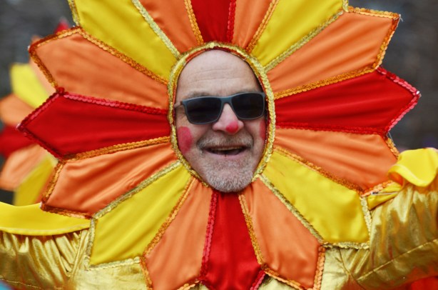 man's face, wearing sunglasses in the middle of an orange and yellow flower, part of Santa Claus parade 