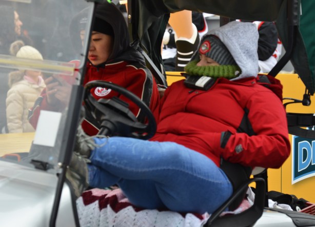 a woman leans back in a golf cart, marshall & crowd control, before the start of a parade, 
