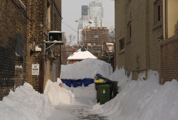 a small alley in winter, garbage bins covered with snow, mounds of snow, 