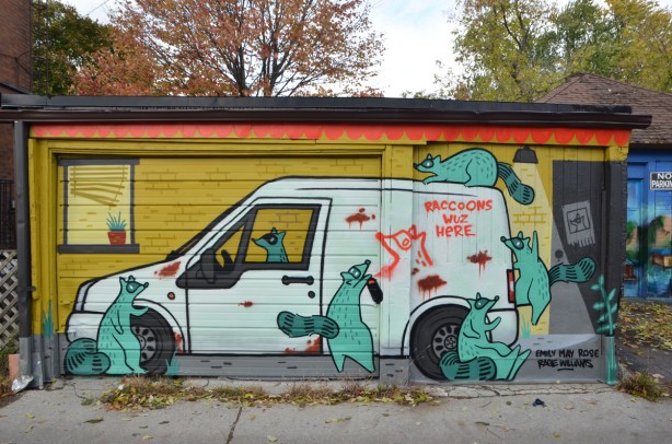 mural on a garage in an alley, Feel Good Lane, by Emily May Rose and of a white van with lots of green raccoons around it, on top of it, and in the drivers seat 