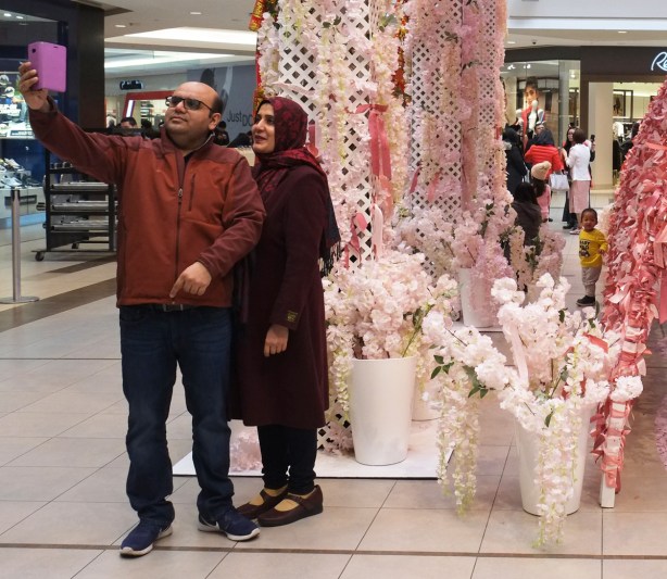 a middle aged muslim couple takes a selfie in front of a lunar new year decoration at Scarborough Town Centre