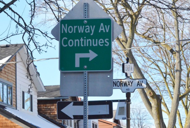 street signs on a post. a one way sign pointing left, a green and white sign that says Norway Ave continues to the right ahead