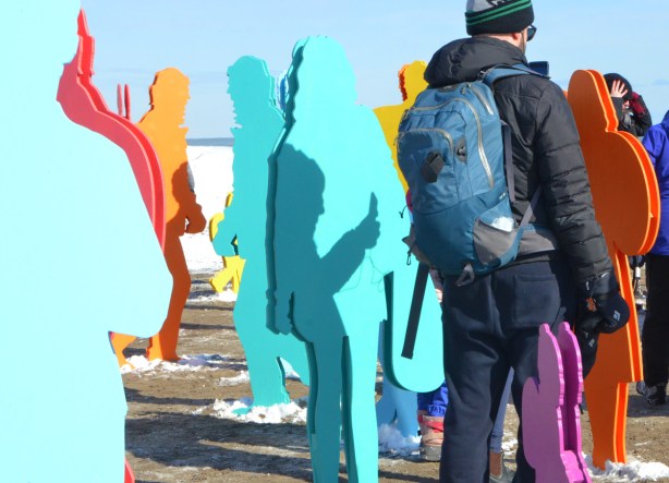 a man and his shadow and many life size cut out figures of people in bright colours