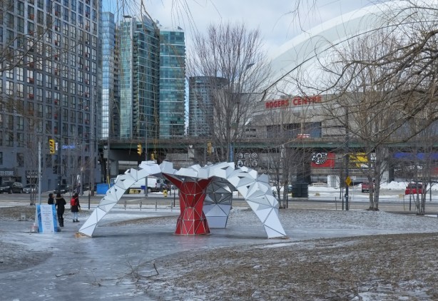 art installation in H2O park, Tripix, a three legged arch struture in red and chrome