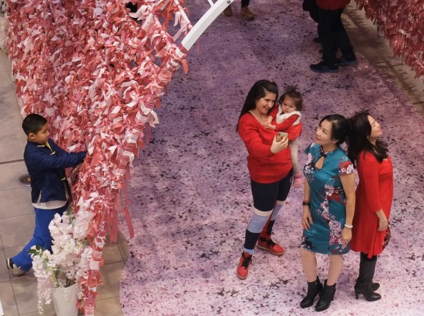 posing in front of a ribbon filled arch