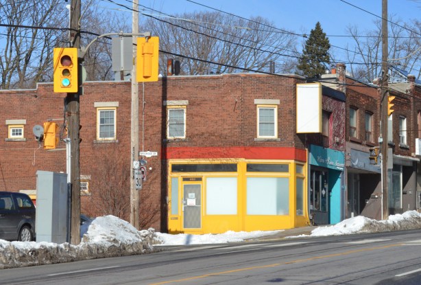 a storefront trimmed in bright yellow and angled at the corner, intersection of Kingston Rd and Brookside