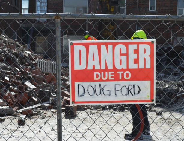 red and white sign, danger due to signs, on a chainlink fence at a construction site in Regent Park, danger due to Doug Ford, premier of Ontario