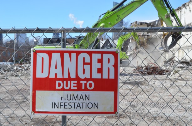 red and white sign, danger due to signs, on a chainlink fence at a construction site in Regent Park, danger due to human infestation