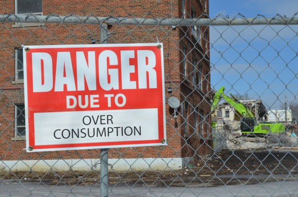 red and white sign, danger due to signs, on a chainlink fence at a construction site in Regent Park, danger due to over consumption