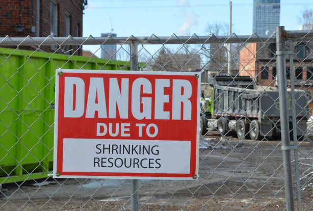 red and white sign, danger due to signs, on a chainlink fence at a construction site in Regent Park, danger due to shrinking resources