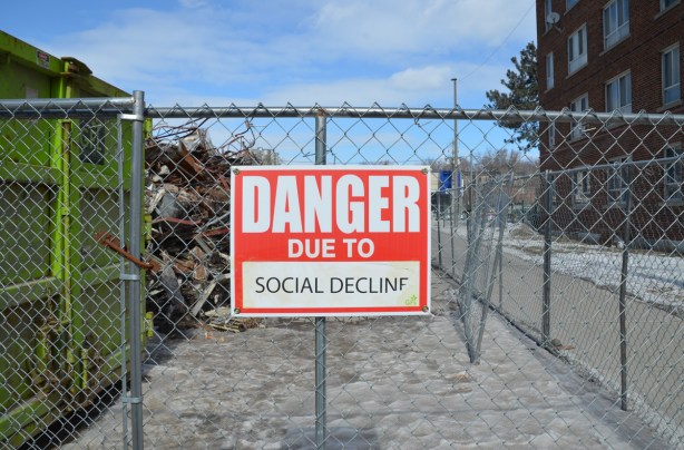 red and white sign, danger due to signs, on a chainlink fence at a construction site in Regent Park, danger due to social decline