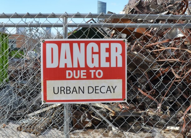 red and white sign, danger due to signs, on a chainlink fence at a construction site in Regent Park, danger due to urban decay