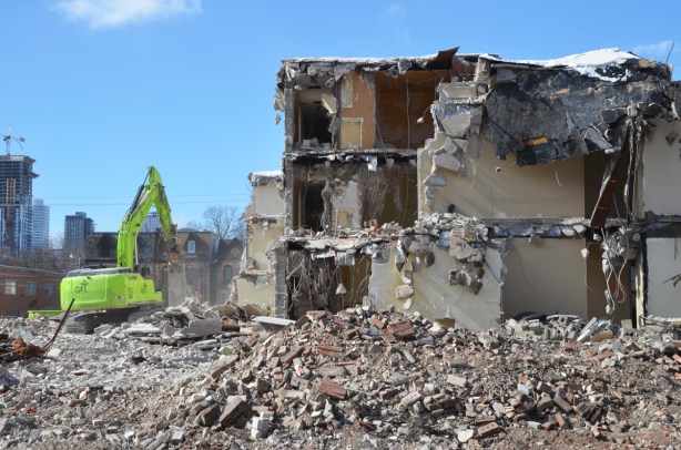green machinery demolishes a building in Regent Park - 3 storeys remaining