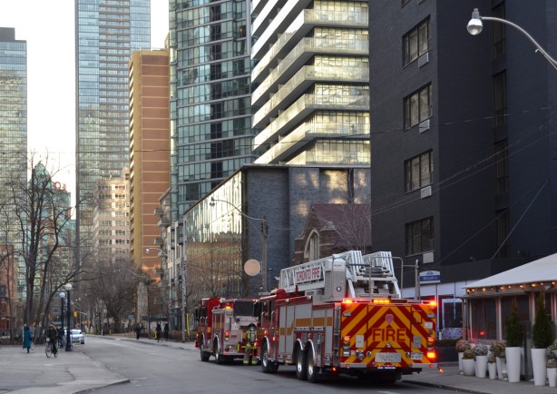 two fire trucks parked on a street of high rise and midsized apartment buildings 