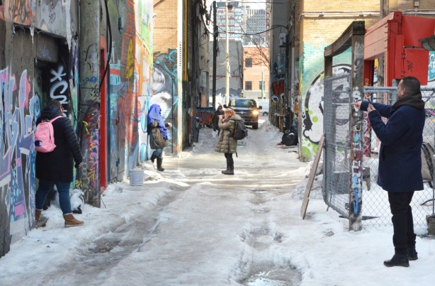 people taking pictures in graffiti alley 