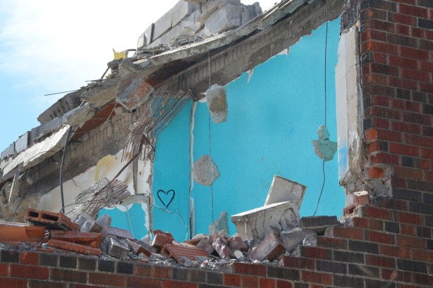 a small black heart drawn on the blue walls of building now being demolished