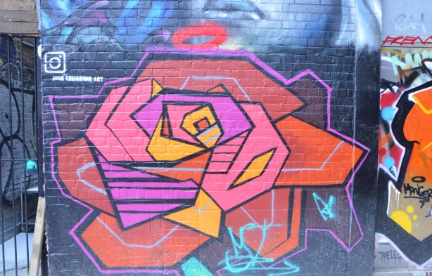 a large stylized rose in a mural in a lane 