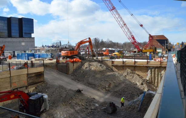 large hole in the ground at a construction site, diggers and a crane onsite 