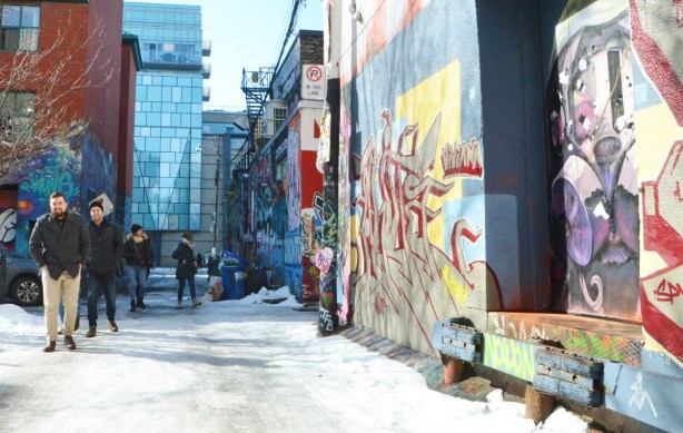 looking down Rush Lane on a winter afternoon, snow and ice on the ground, some people walking