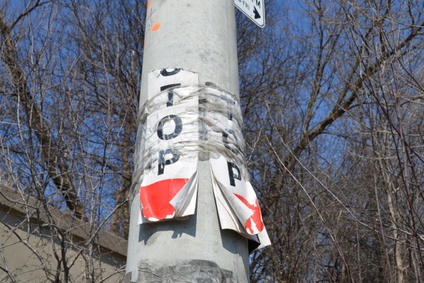 concrete utility pole with two ripped paper temporary bust stop signs, TTC, stops no longer in use 