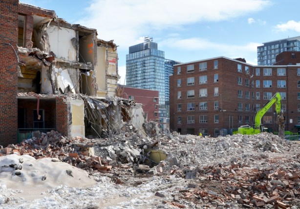 partially demolished brick building in front of an empty building waiting to be demolished 