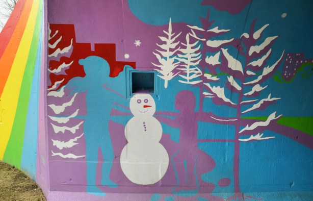 scenes from the mural painted inside the rainbow arch bridge - blue and purple children build a white snowman with white trees in the background