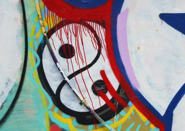 close up of a spray paint artwork in alley, a yin yang symbol in black and white with red drips of paint running through it 