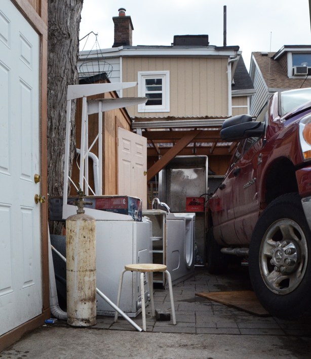 a red truck parked in an alley with a lot of stuff beside it
