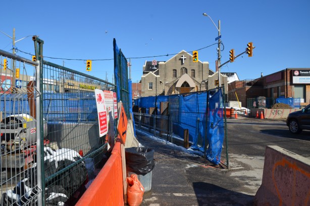 blue fences between sidewalk and rad at Eglinton and Dufferin, construction, church in the background, 