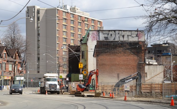 construction on dundas street, a vacant lot where a building was demolished, construction equipment and a dump truck working at the site, old building beside 