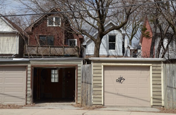 open garage door with a window at the back of the garage, other garage beside it has closed door, can also see back of the two houses 