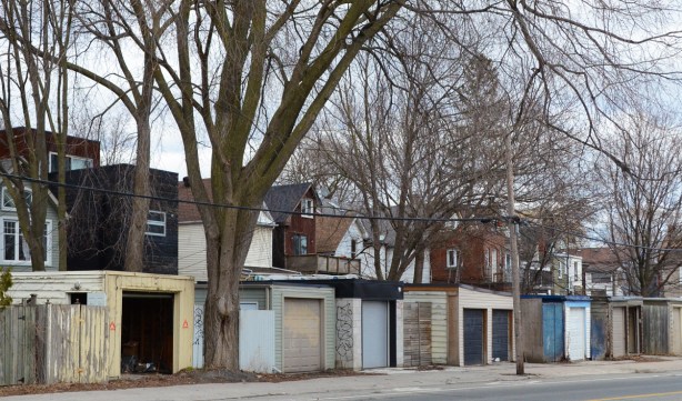 row of garages facing onto the street, backs of houses and a very large tree