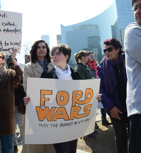 person holding a placard protesting Doug Fords proposed cuts to education funding, signs says Ford Wars