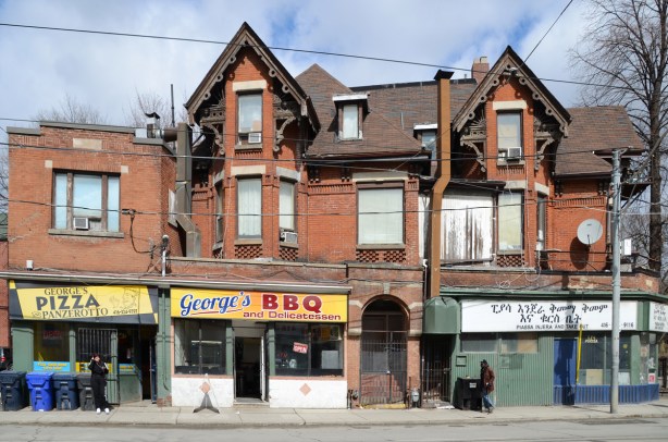 a large old victorian brick building, once a large house now divided up, 3 restaurants at street level, Georges Pizza, Georges BBQ, and one in a foreign alphabet, Ethiopian restaurant Piassa Injera