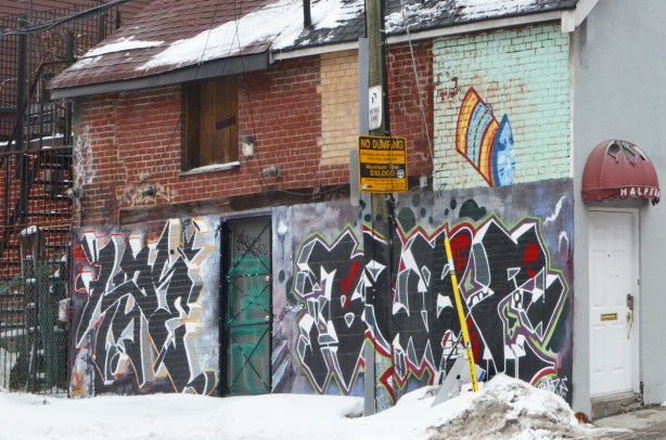 text street art on the lower level of a building in a lane 