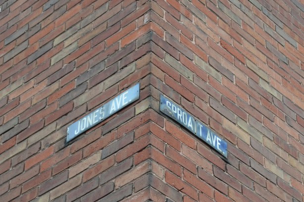 two old Toronto street signs, blue metal, attached to a house at Jones Ave and Sproat Ave