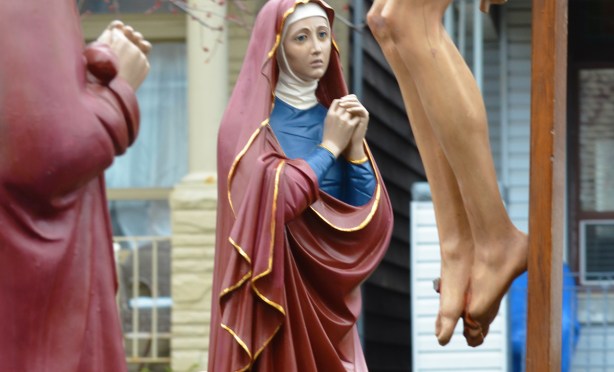 a statue of mary looking a statue of Christ on the cross in a parade
