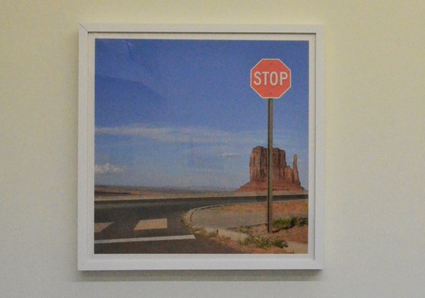 a large frames photo on a wall of rock formation in Monument Valley USA with a stop sign in the foreground