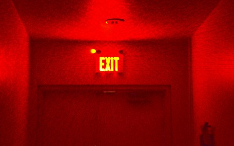 a red exit sign lights up a dark doorway, all red 