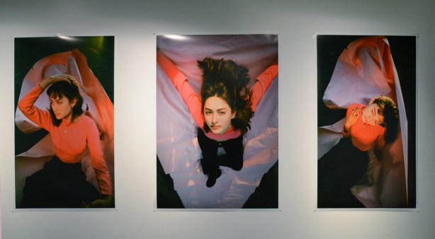a triptych, three photos, of a woman in an orange long sleeved top, long brown hair, black pants, in three different poses, 