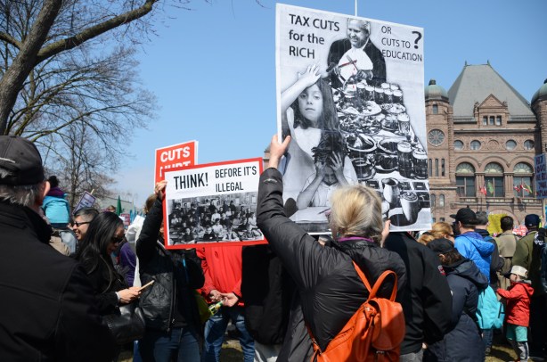 person holding a placard protesting Doug Fords proposed cuts to education funding, Crowds at a protest at Queens Park, 