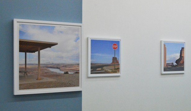 three paintings by Emmanuel Monzon on a wall in gallery, pictures of empty places, or where urban sprawl seems to take over deserted places 