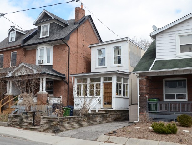 a tiny, narrow, two storey house beside a larger brick house