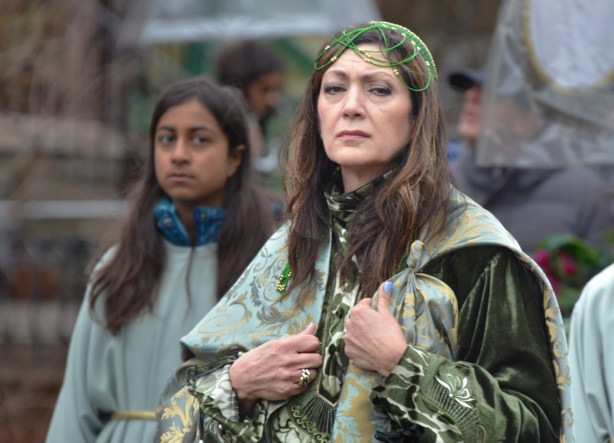 two women in a parade. The one in front is wearing an elaborate green outfit (only top part can be seen)
